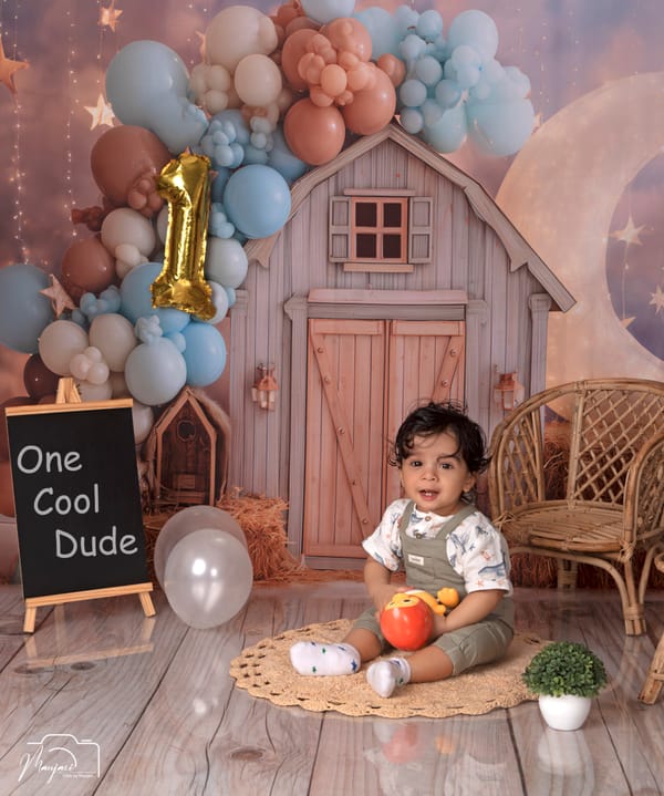 Toddler at a rustic barn set with a gold number-one balloon