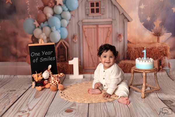Smiling baby beside a blue first-birthday cake at a starry barn set