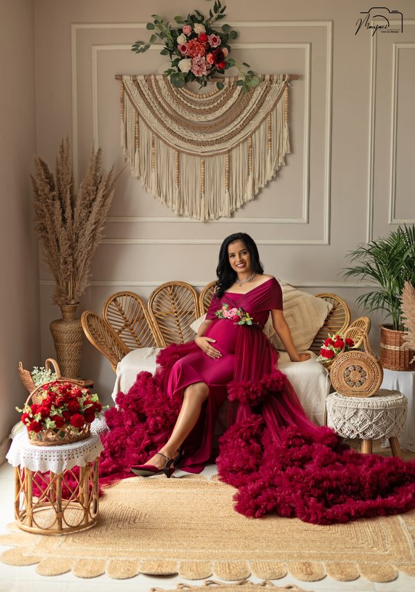 Expectant mother in a magenta ruffled gown on a rattan boho set