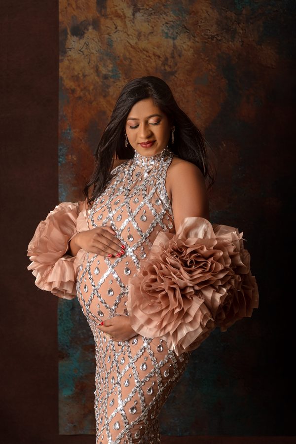 Maternity portrait in a sequinned gown with blush ruffled sleeves