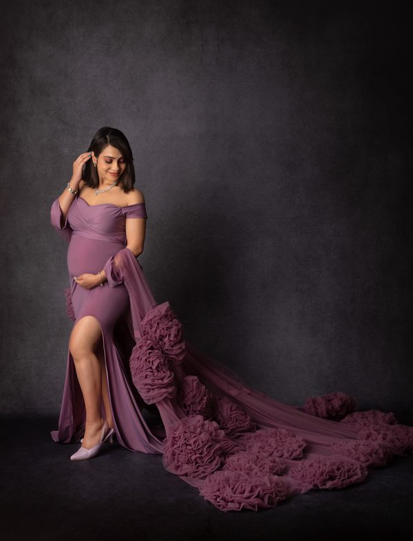 Maternity portrait in a plum gown with a long ruffled train