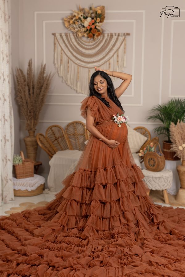 Expectant mother in a rust ruffled gown with a sweeping train