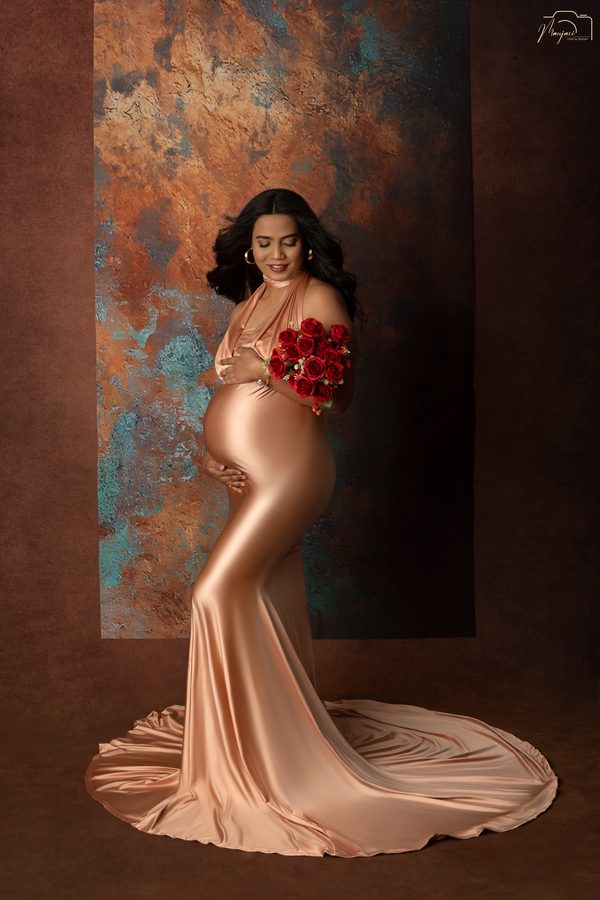 Maternity portrait in a bronze satin gown holding red roses
