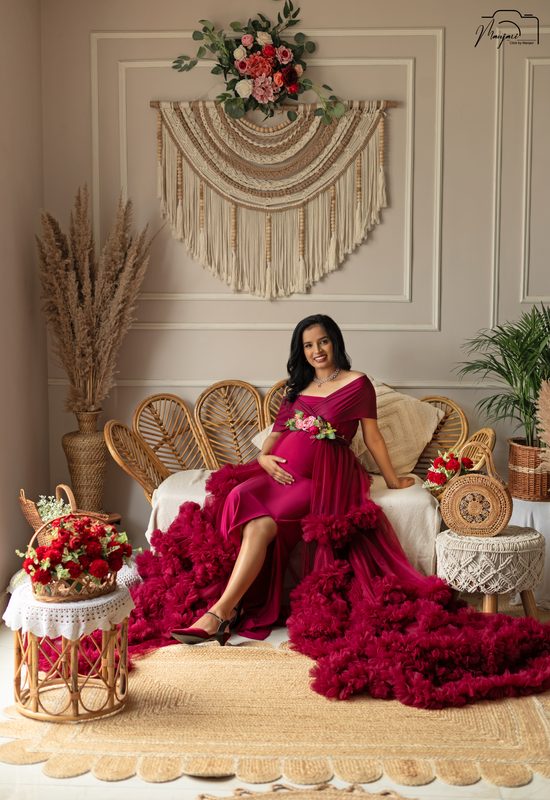 Expectant mother in a magenta ruffled gown on a rattan boho set
